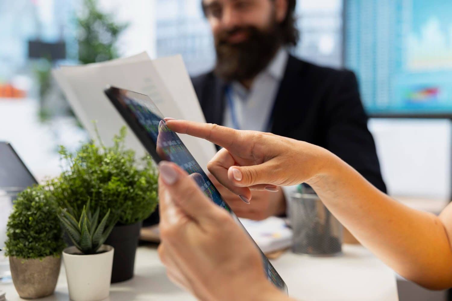 kobieta trzymająca tablet z leasing-management-system, w tle mężczyzna przeglądający dokumenty